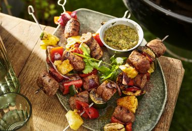 Brochetas de carne y ananá asado acompañadas de salsa