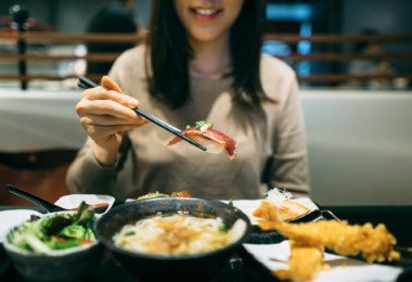 Mujer degustas sushi de calamar de tubo pequeño, otro de los tipos de calamar.