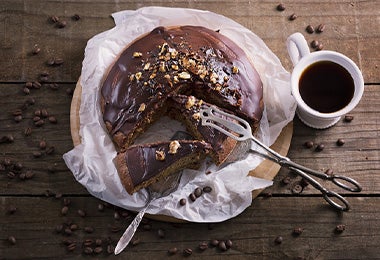 Tarta Sacher acompañada de café negro y servido con unas pinzas de cocina.