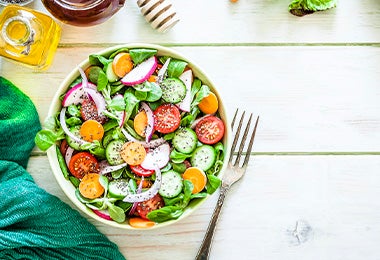 Ensalada mediterránea con vinagreta en toma cenital sobre una mesa verdosa