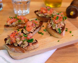 Montaditos con atún, tomate fresco y hierbas, servidos en tabla