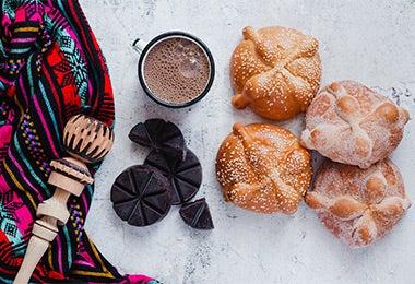 Cuatro panes rellenos junto con una taza de chocolate, todos cocinados con cardamomo