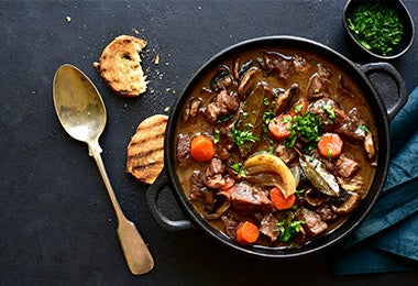 Plato con estofado de carnes y verduras con hojas de laurel