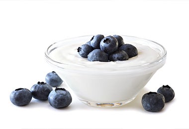 Yogur griego con arándanos sobre un fondo blanco, una merienda para diabéticos