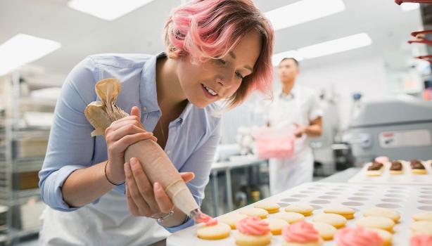 Mujer agrega relleno a galletitas con manga pastelera