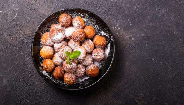 Plato de buñuelos de mandioca espolvoreados vistos desde un ángulo cenital.