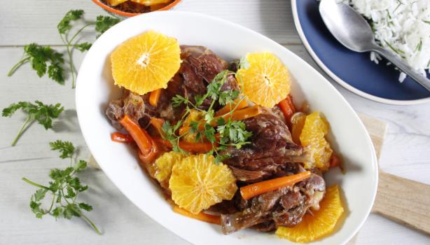 Plato de cerdo con salsa de naranja, acompañado de rodajas de naranja